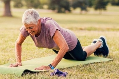 Image of a senior lady performing push-ups outdoors.