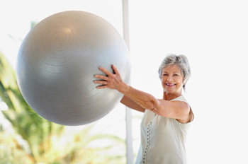Image of a female older adult exercising with a gym ball.