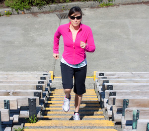Image of a female fitness client performing stair-based exercises outdoors.